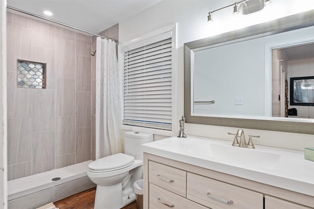 bathroom featuring toilet, a tile shower, and vanity