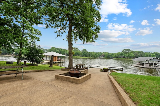 view of home's community with a yard, a boat dock, a water view, and an outdoor fire pit