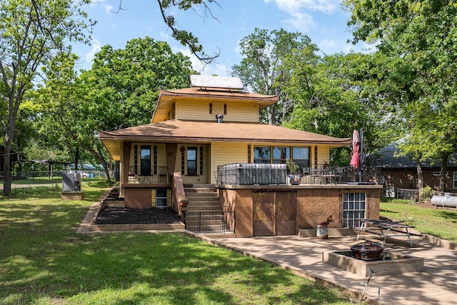 rear view of house with a porch, an outdoor fire pit, a yard, stairs, and fence