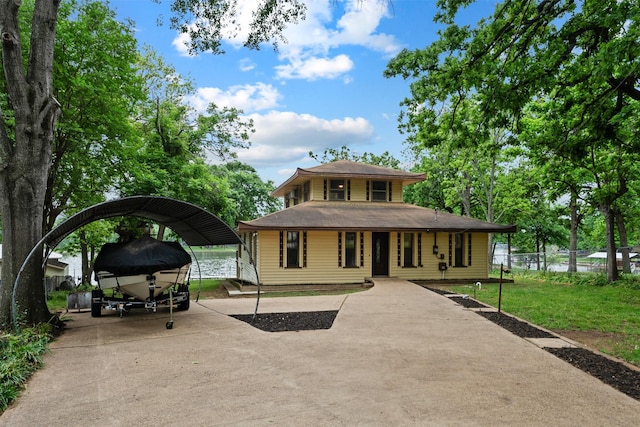 view of front of property featuring fence, concrete driveway, a detached carport, and a front lawn