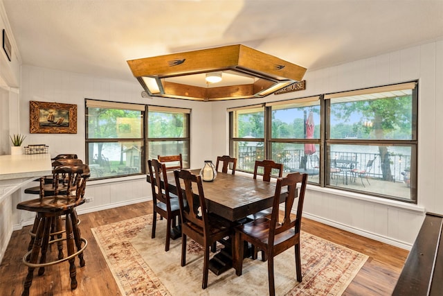 dining area with wood finished floors, a healthy amount of sunlight, and a decorative wall