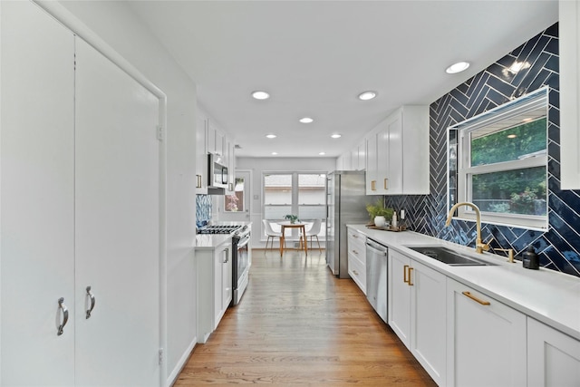 kitchen with a sink, appliances with stainless steel finishes, a wealth of natural light, and white cabinetry