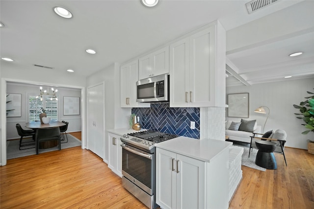 kitchen with decorative backsplash, light wood-style flooring, white cabinets, appliances with stainless steel finishes, and light countertops