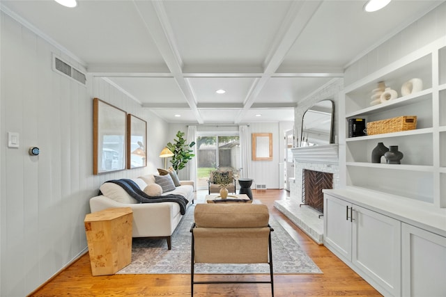 living room with beam ceiling, visible vents, light wood-style floors, and a fireplace