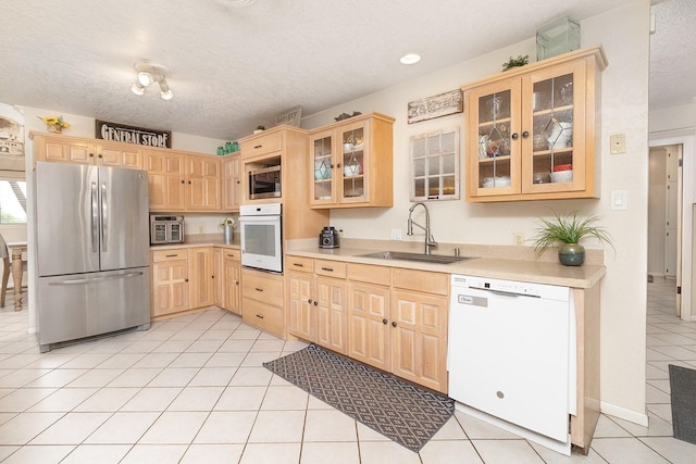 2108 Menard, Brady, TX 76825 - kitchen with appliances with stainless steel finishes, light brown cabinetry, a sink, light tile patterned floors, and light countertops