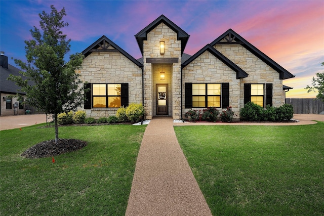 view of front of house featuring fence, a yard, and stone siding