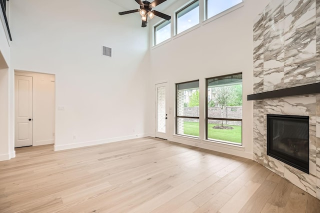 16090 Inca Dove Ct, Frisco, TX 75035 - unfurnished living room featuring a high ceiling, light wood finished floors, a ceiling fan, a fireplace, and baseboards