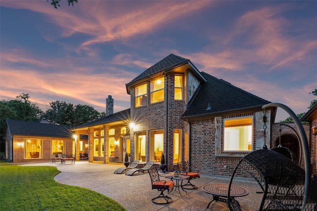 7307 Stallion Cir, Flower Mound, TX 75022 - back of house at dusk with a chimney, a patio area, and brick siding