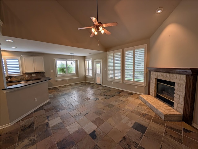 unfurnished living room featuring ceiling fan, stone tile flooring, baseboards, recessed lighting, and a stone fireplace