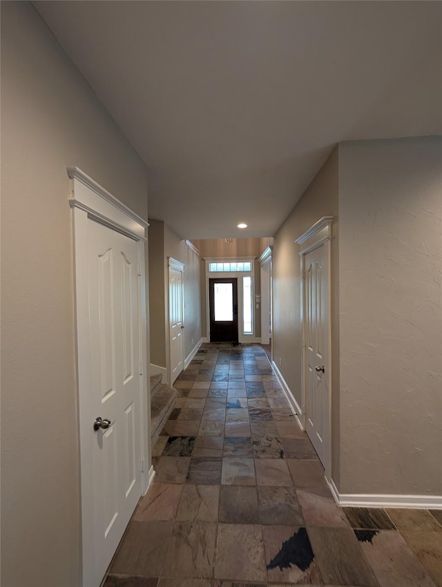 doorway to outside featuring stone tile flooring and baseboards