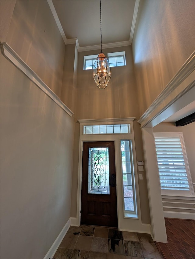 entryway featuring an inviting chandelier, baseboards, ornamental molding, and a high ceiling
