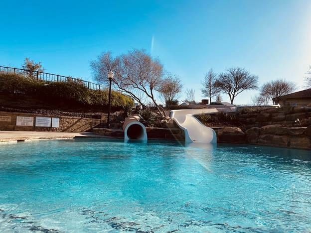 community pool featuring a water slide and fence