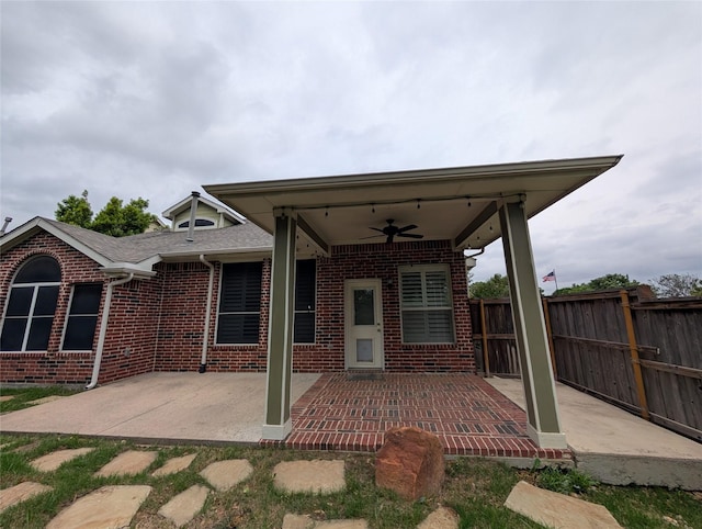 rear view of property featuring brick siding, a ceiling fan, fence, and a patio area