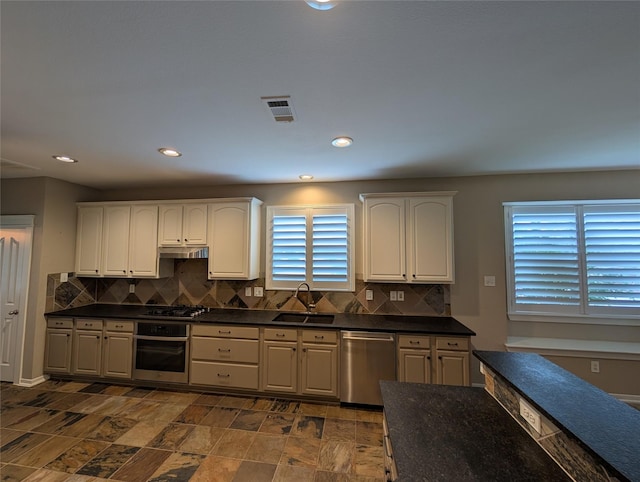 kitchen with tasteful backsplash, a sink, dark countertops, visible vents, and stainless steel appliances