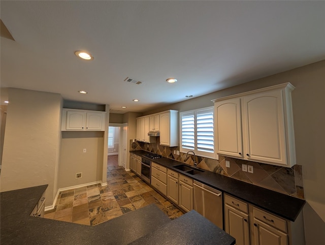 kitchen with a sink, dark countertops, visible vents, and stainless steel appliances