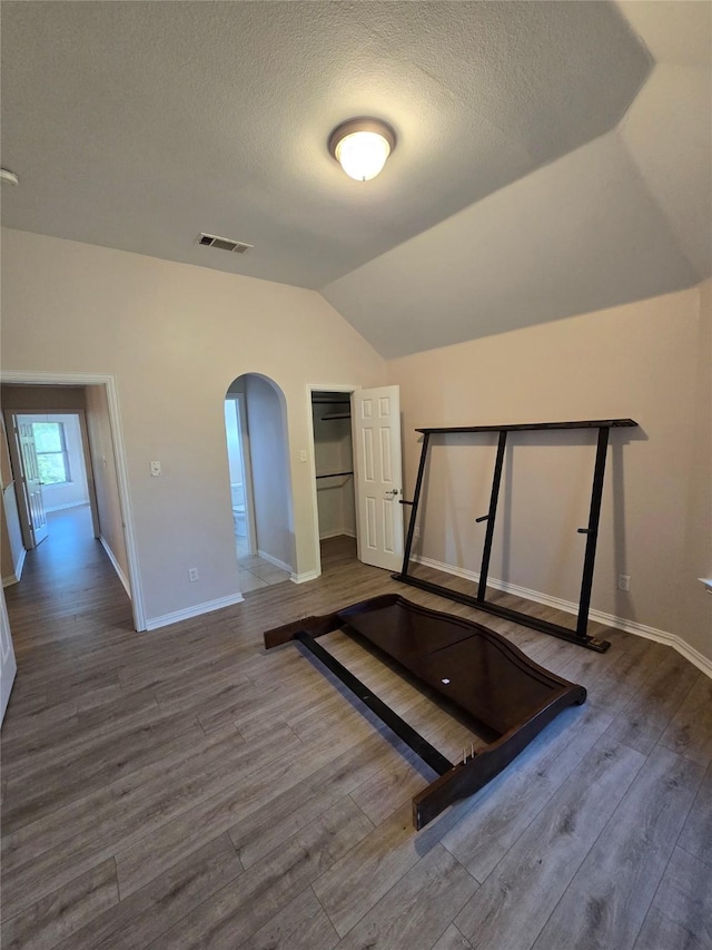 1264 Carriage Creek Dr, Desoto, TX 75115 - exercise area featuring lofted ceiling, arched walkways, wood finished floors, baseboards, and a textured ceiling