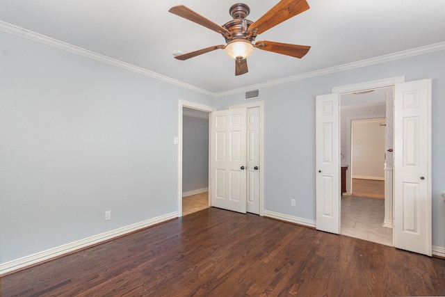 unfurnished bedroom featuring crown molding, baseboards, wood finished floors, and visible vents