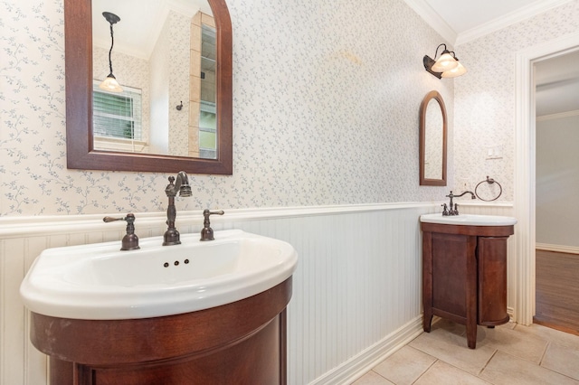 bathroom with crown molding, a sink, tile patterned flooring, wallpapered walls, and two vanities