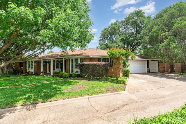 ranch-style house featuring a garage, a front lawn, fence, covered porch, and concrete driveway