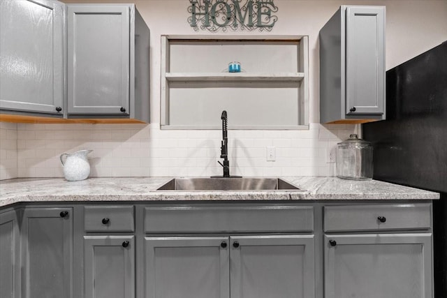kitchen with gray cabinetry, tasteful backsplash, and a sink