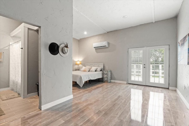 bedroom featuring light wood-style floors, access to exterior, baseboards, an AC wall unit, and french doors