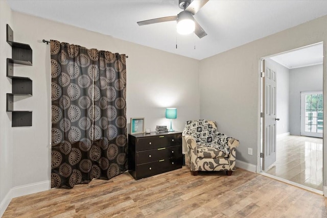 living area with a ceiling fan, wood finished floors, and baseboards