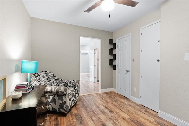 living area with wood finished floors, a ceiling fan, and baseboards