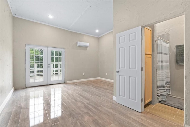unfurnished living room with light wood-style floors, a wall mounted AC, baseboards, french doors, and crown molding