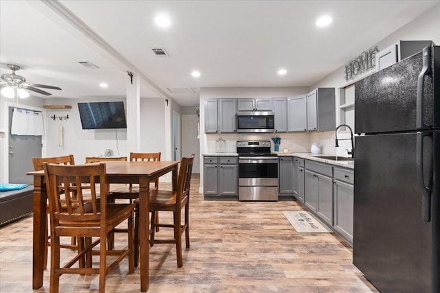kitchen with a sink, appliances with stainless steel finishes, visible vents, gray cabinetry, and light wood finished floors