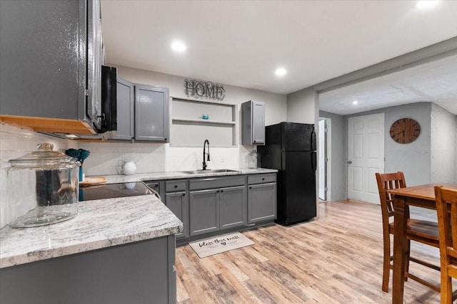 kitchen with tasteful backsplash, freestanding refrigerator, open shelves, a sink, and gray cabinetry