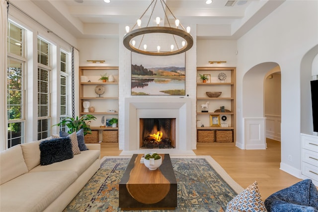 5409 Twin Cities Ln, Mckinney, TX 75070 - living room with light wood-type flooring, a fireplace with flush hearth, a chandelier, arched walkways, and recessed lighting