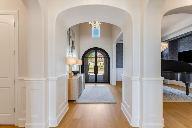 5409 Twin Cities Ln, Mckinney, TX 75070 - entrance foyer featuring light wood-style flooring, arched walkways, a decorative wall, and wainscoting