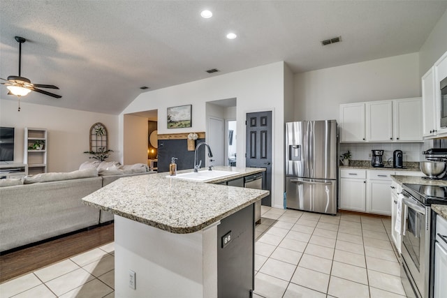 kitchen with appliances with stainless steel finishes, a sink, open floor plan, light tile patterned floors, and visible vents