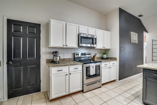kitchen featuring light tile patterned floors, appliances with stainless steel finishes, light stone countertops, and white cabinetry