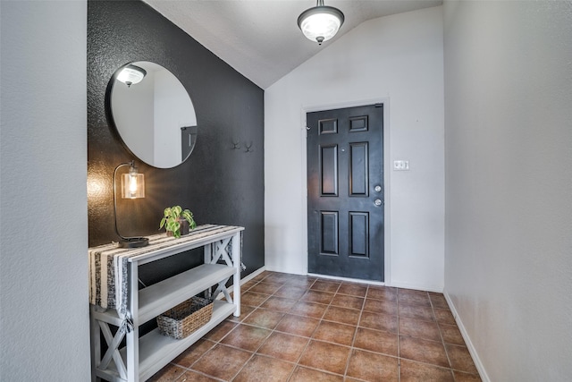 entryway featuring tile patterned floors, baseboards, and vaulted ceiling