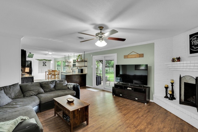 608 Timothy Dr, Fort Worth, TX 76028 - living room featuring a brick fireplace, crown molding, a ceiling fan, baseboards, and wood finished floors