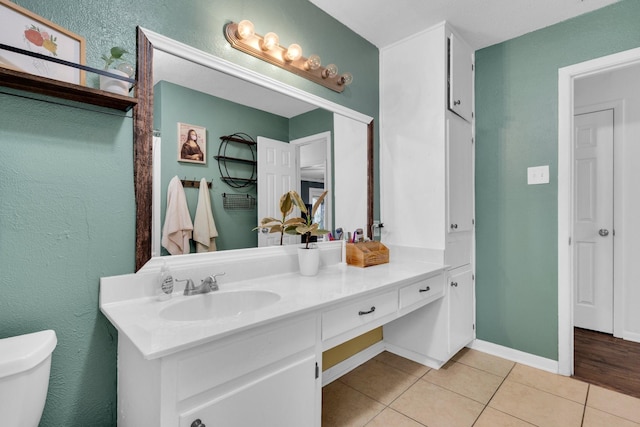 608 Timothy Dr, Fort Worth, TX 76028 - bathroom featuring vanity, toilet, a textured wall, baseboards, and tile patterned flooring