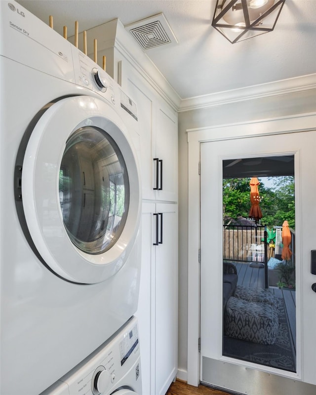 laundry area with cabinet space, stacked washer / drying machine, visible vents, and crown molding
