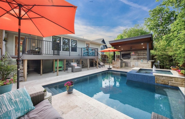 pool with exterior kitchen, an in ground hot tub, an outdoor hangout area, and a patio area
