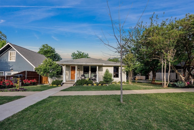 view of front of house featuring a porch, fence, and a front lawn