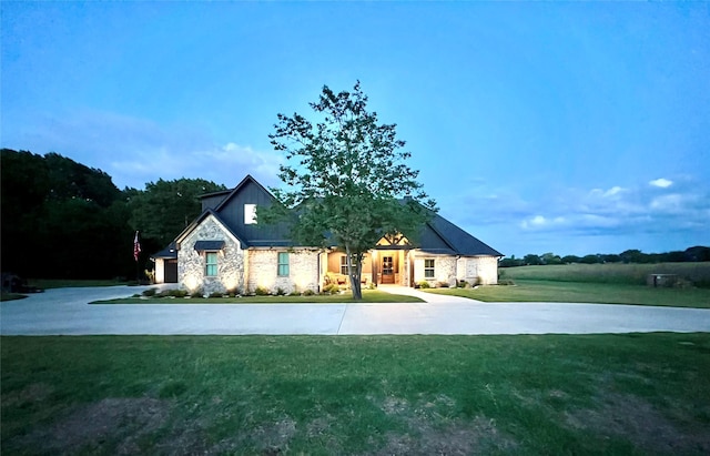 view of front facade with curved driveway, a front lawn, and stone siding