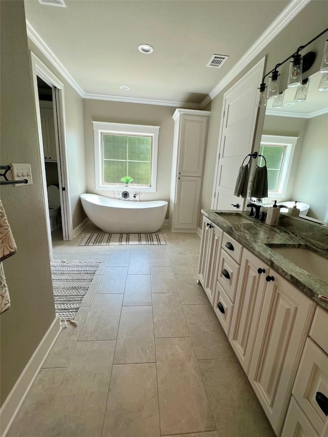 bathroom with ornamental molding, visible vents, a freestanding bath, and baseboards