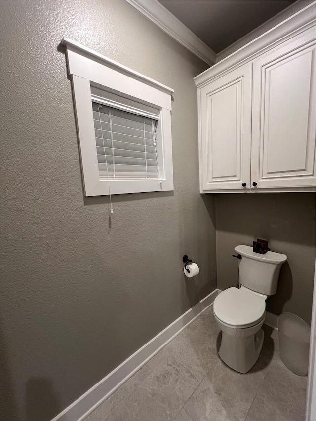 bathroom featuring toilet, ornamental molding, and baseboards
