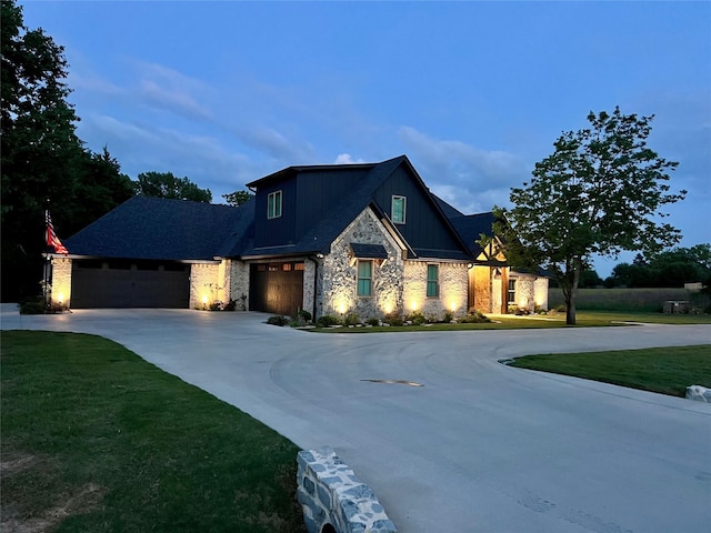 view of front of property featuring a front yard, concrete driveway, and stone siding