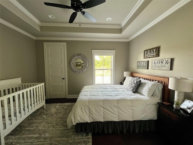bedroom featuring ornamental molding, a ceiling fan, wood finished floors, and a tray ceiling