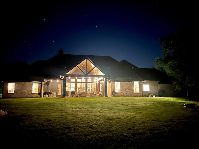 back of house at twilight featuring a lawn