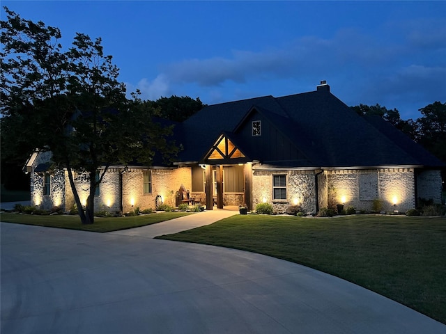 view of front of house with a chimney, a front lawn, and stone siding