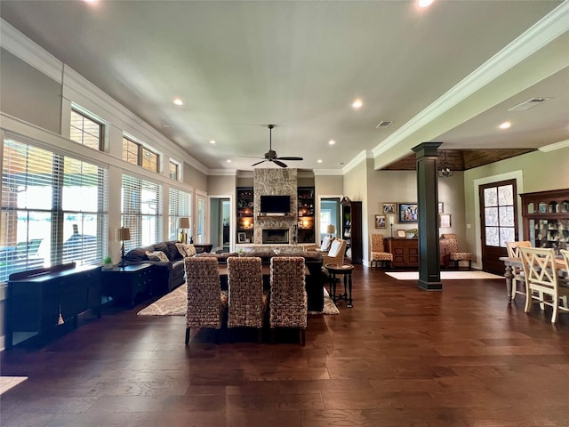 living area with dark wood-type flooring, decorative columns, ceiling fan, and crown molding