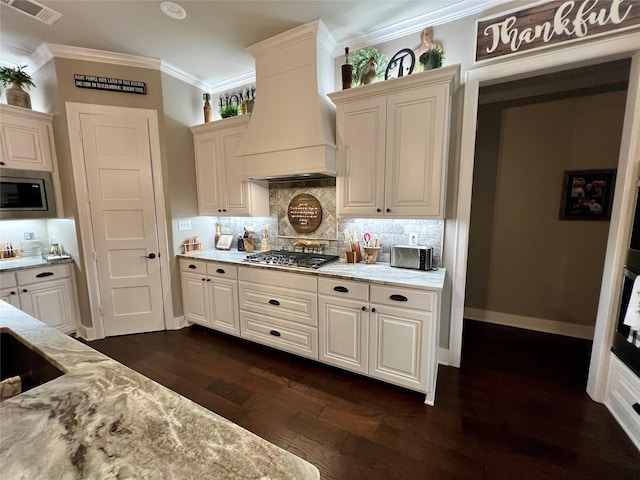 kitchen featuring decorative backsplash, custom range hood, appliances with stainless steel finishes, crown molding, and dark wood-type flooring