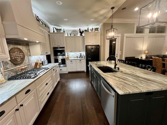 kitchen featuring decorative backsplash, custom range hood, a sink, appliances with stainless steel finishes, and light stone countertops